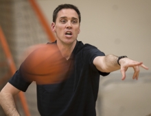 Men’s basketball coach Landry Kosmalski with a basketball in front of him he named NCAA Division III National Coach of the Year.